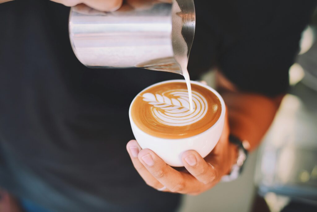 Money beliefs, how to identify them and how they affect your decisions Close-up of a barista pouring latte art into a coffee cup indoors.