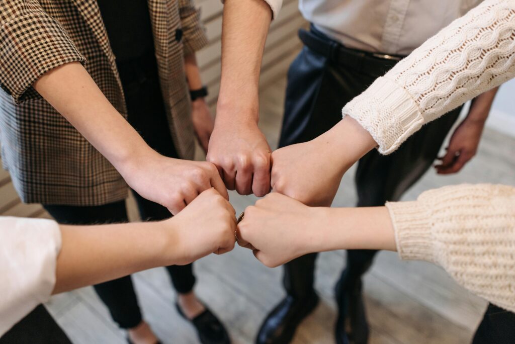 when a coach or personal finance program might be right Five people uniting hands indoors, symbolizing teamwork and unity.