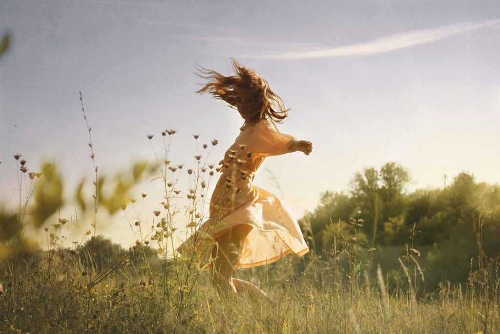 There is no “right” and “wrong” with personal finance, just what is right FOR YOU A carefree young woman in a dress dances joyfully in a sunlit meadow.