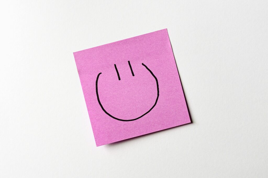 The money framework we all need, how to start building and updating it as we move through financial seasons A simple smiley face drawn on a pink sticky note against a white background.